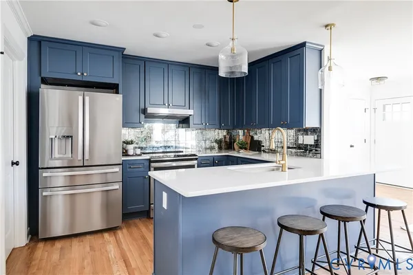 a kitchen with stainless steel appliances a table chairs refrigerator and wooden cabinets