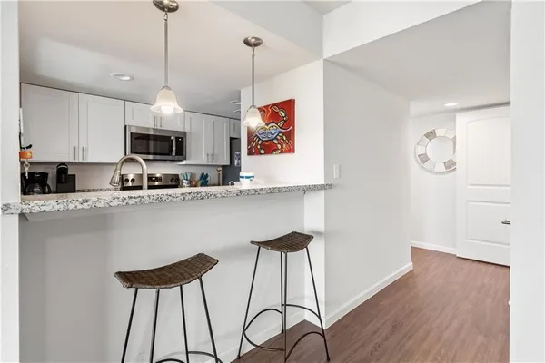 a kitchen with stainless steel appliances kitchen island a refrigerator and a wooden floor