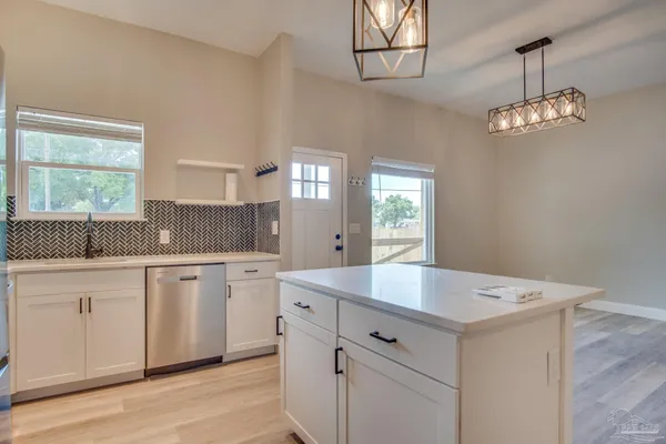a hall with kitchen island white cabinets and chandelier