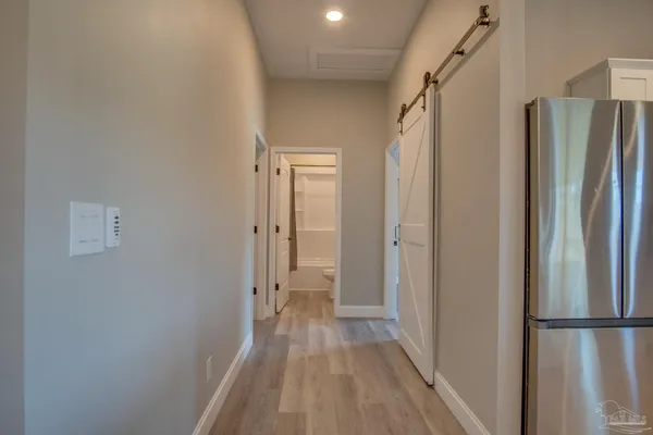 a view of a hallway with wooden floor and a refrigerator