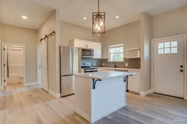 a kitchen with stainless steel appliances granite countertop a refrigerator a stove a sink dishwasher a refrigerator and white cabinets with wooden floor