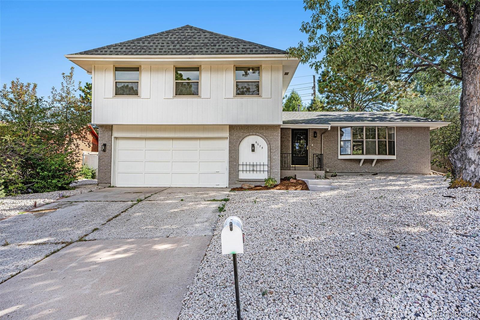 6075 Castlewood Lane Colorado Springs, CO 80918 - Photo 1 of 23 a front view of a house with a yard and garage