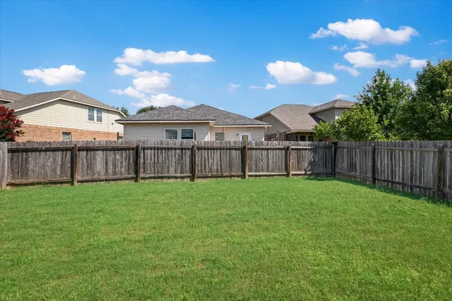 a view of a backyard with table and chairs and wooden fence