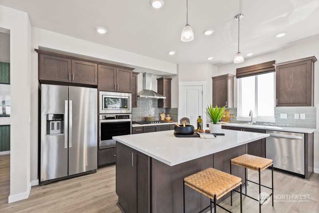 4414 228th Place South East, Unit MC5 Bothell, WA 98021 - Photo 10 of 33 a kitchen with a sink a kitchen island wooden floor cabinets and appliances