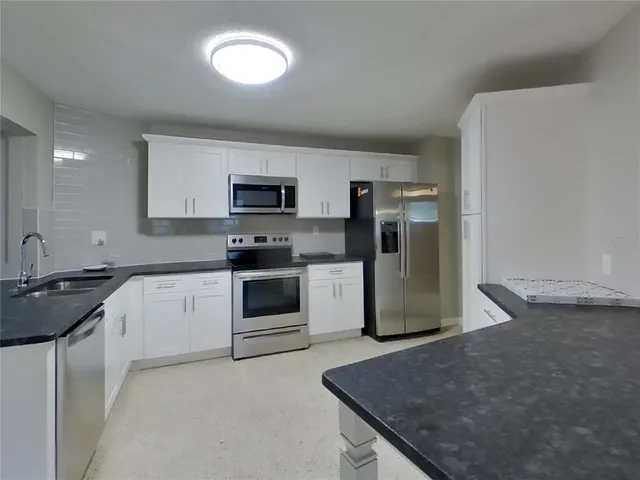 a kitchen with kitchen island a sink stainless steel appliances and white cabinets