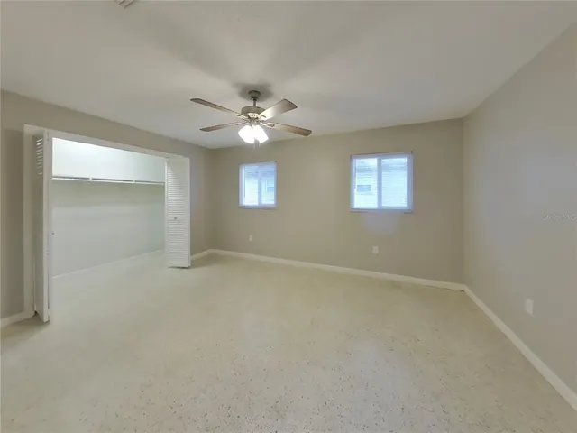 an empty room with windows and ceiling fan