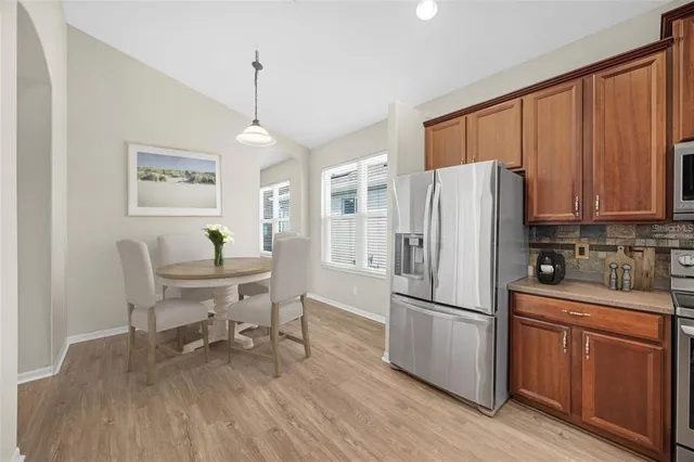 a kitchen with stainless steel appliances granite countertop a refrigerator a stove a sink dishwasher and wooden cabinets with wooden floor