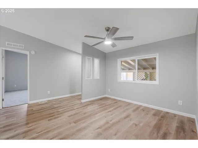 a view of an empty room with window and wooden floor