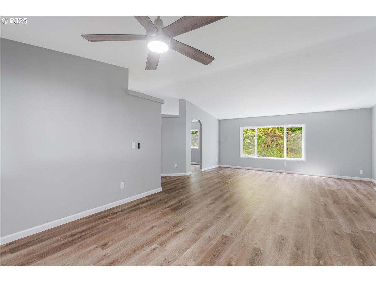 369 Gun Club Road, Unit 117 Woodland, WA 98674 - Photo 8 of 29 an empty room with wooden floor chandelier fan and windows