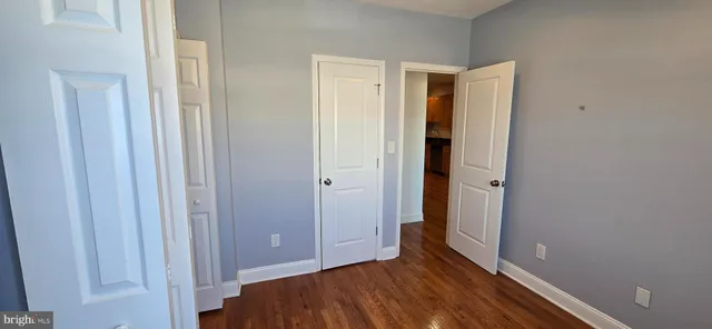 a view of an empty room with closet and wooden floor