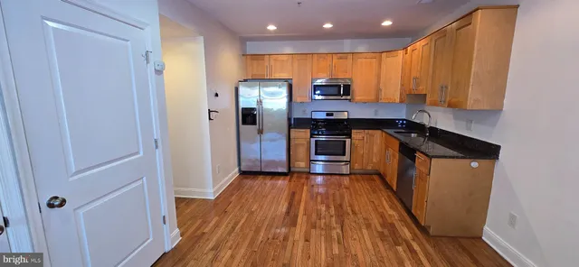 a kitchen with stainless steel appliances a refrigerator and wooden floor