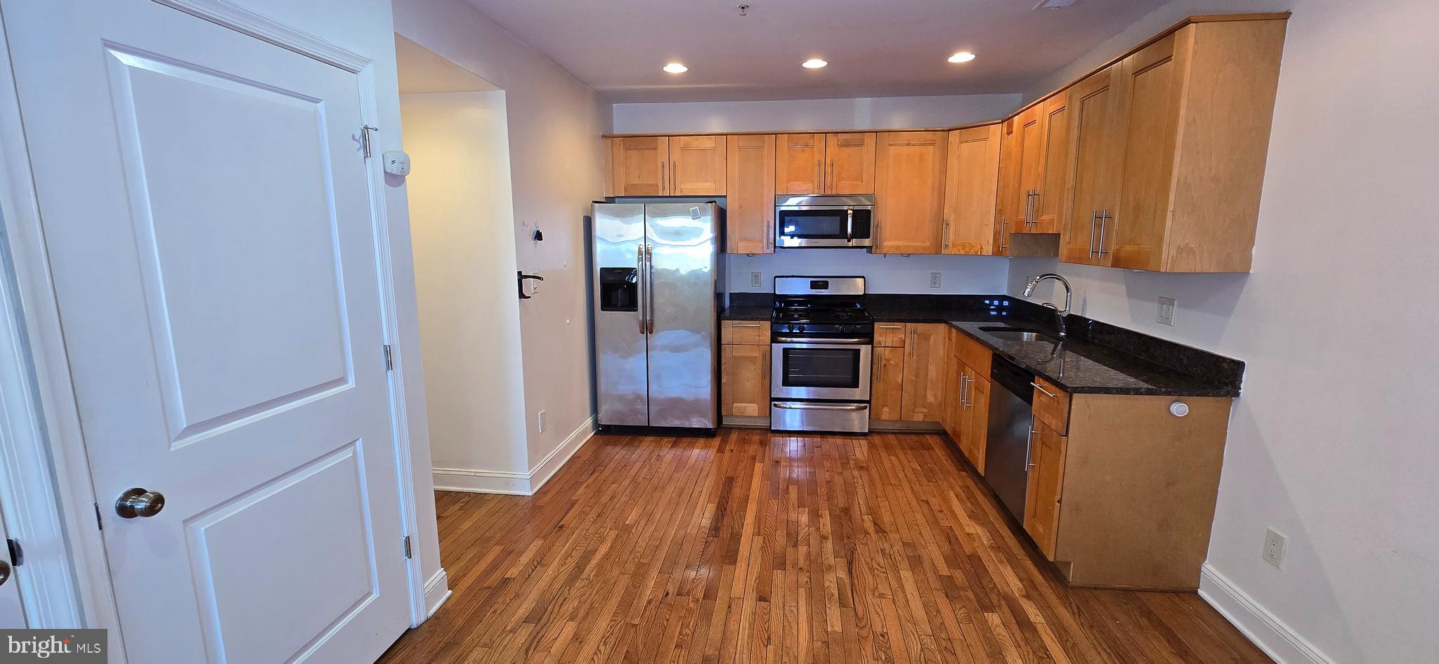 1835 Benning Road Northeast, Unit 1 Washington, DC 20002 - Photo 4 of 12 a kitchen with stainless steel appliances a refrigerator and wooden floor