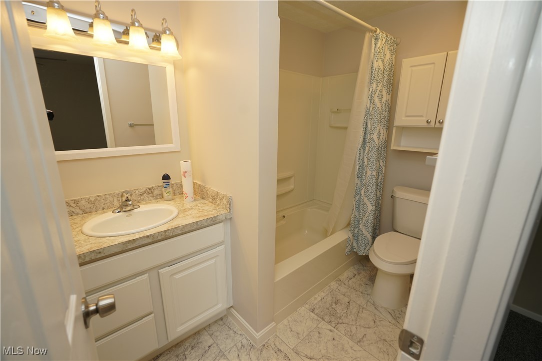 8749 West Ridge Road Elyria, OH 44035 - Photo 9 of 16 Bathroom featuring vanity, marble look tiles, and shower / bath combination with curtain