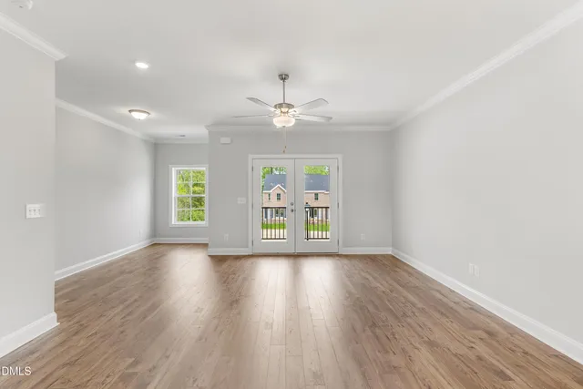 a view of an empty room with a window and wooden floor