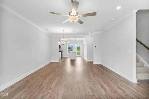 a view of an empty room with wooden floor and a ceiling fan
