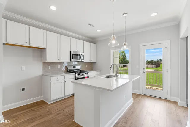 a kitchen with kitchen island granite countertop a stove a sink a center island and cabinets