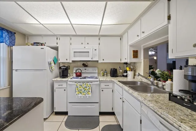 a kitchen with a refrigerator a stove a sink dishwasher and white cabinets with wooden floor
