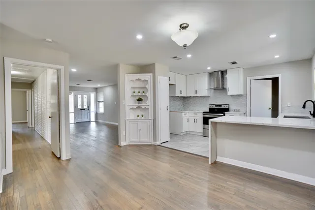 an empty room with wooden floor ceiling fan and windows