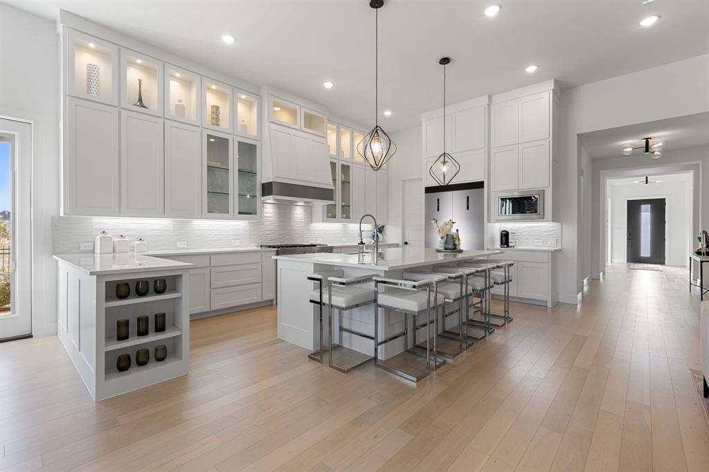 270 Peach Pt Road Prosper, TX 75078 - Photo 8 of 40 a large white kitchen with stainless steel appliances a large center island attached withe living room