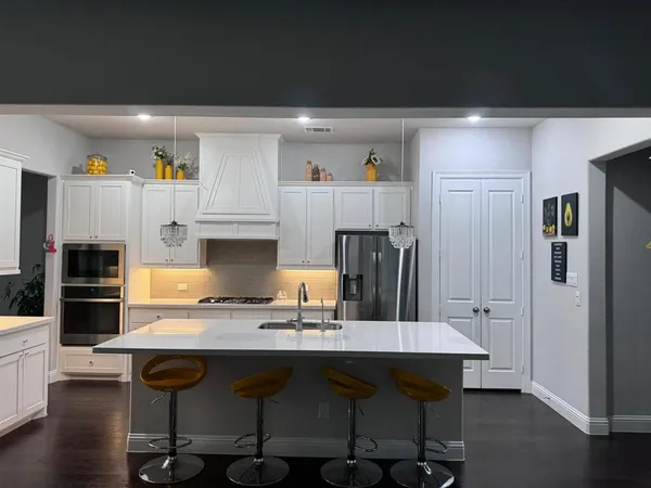 a kitchen with granite countertop a refrigerator stove microwave and cabinets