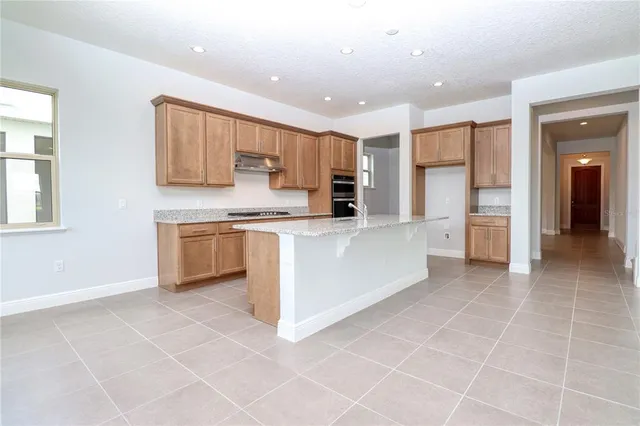 a large kitchen with stainless steel appliances granite countertop a stove a sink and a refrigerator