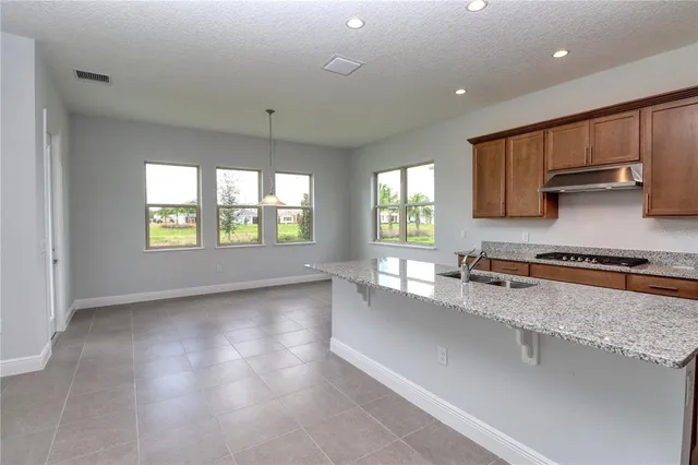 a kitchen with granite countertop kitchen island a sink dishwasher a stove and large window with wooden floor
