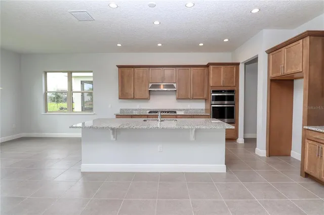 a kitchen with stainless steel appliances granite countertop a sink a stove and a wooden cabinets