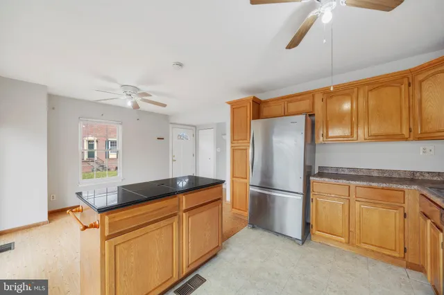 a kitchen with granite countertop a refrigerator a sink and white cabinets