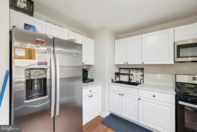 a kitchen with stainless steel appliances white cabinets sink and wooden floor