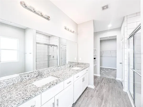 a bathroom with a granite countertop sink a toilet a large mirror and shower