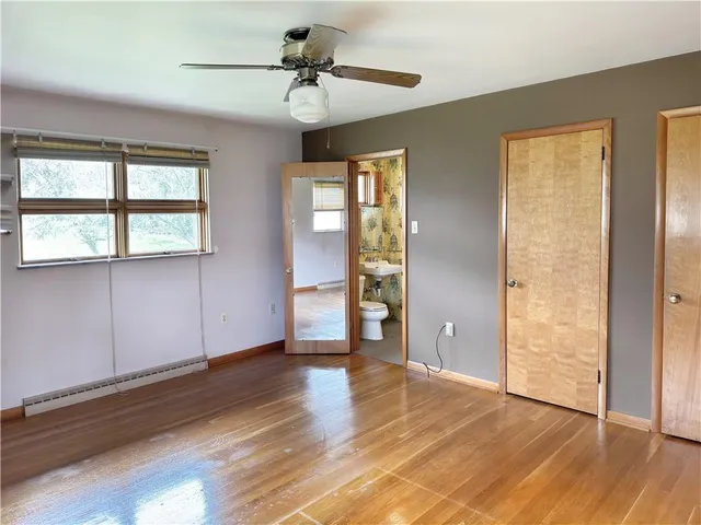 a view of an empty room with window and wooden floor