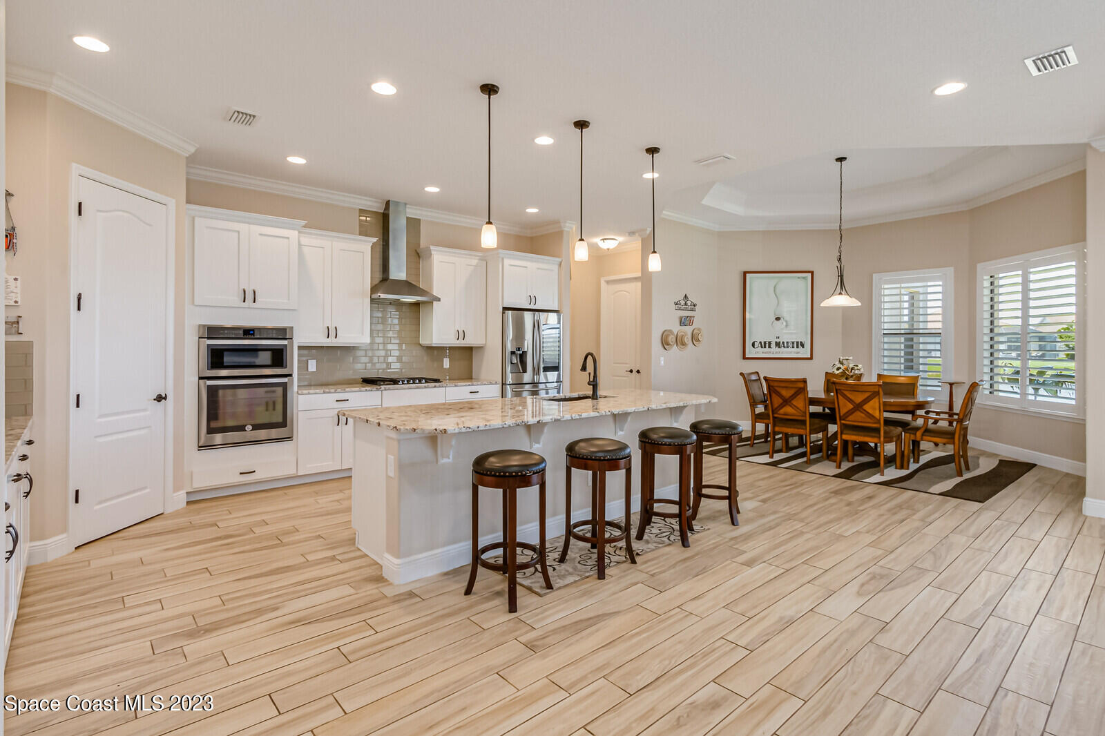 2928 Addison Drive Melbourne, FL 32940 - Photo 18 of 69 a kitchen with stainless steel appliances kitchen island granite countertop a stove a sink a dining table and chairs with wooden floor