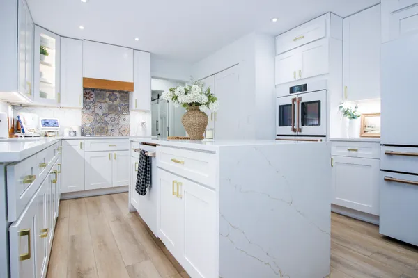 a kitchen with kitchen island granite countertop a white stove top oven a sink with white cabinets and wooden floor