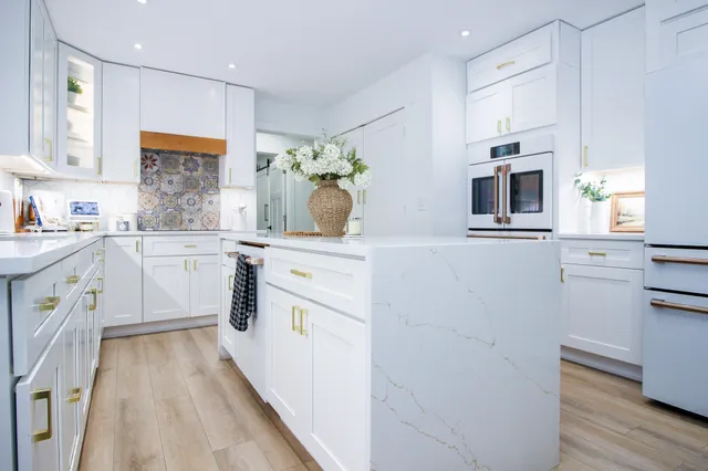 a kitchen with kitchen island granite countertop a white stove top oven a sink with white cabinets and wooden floor