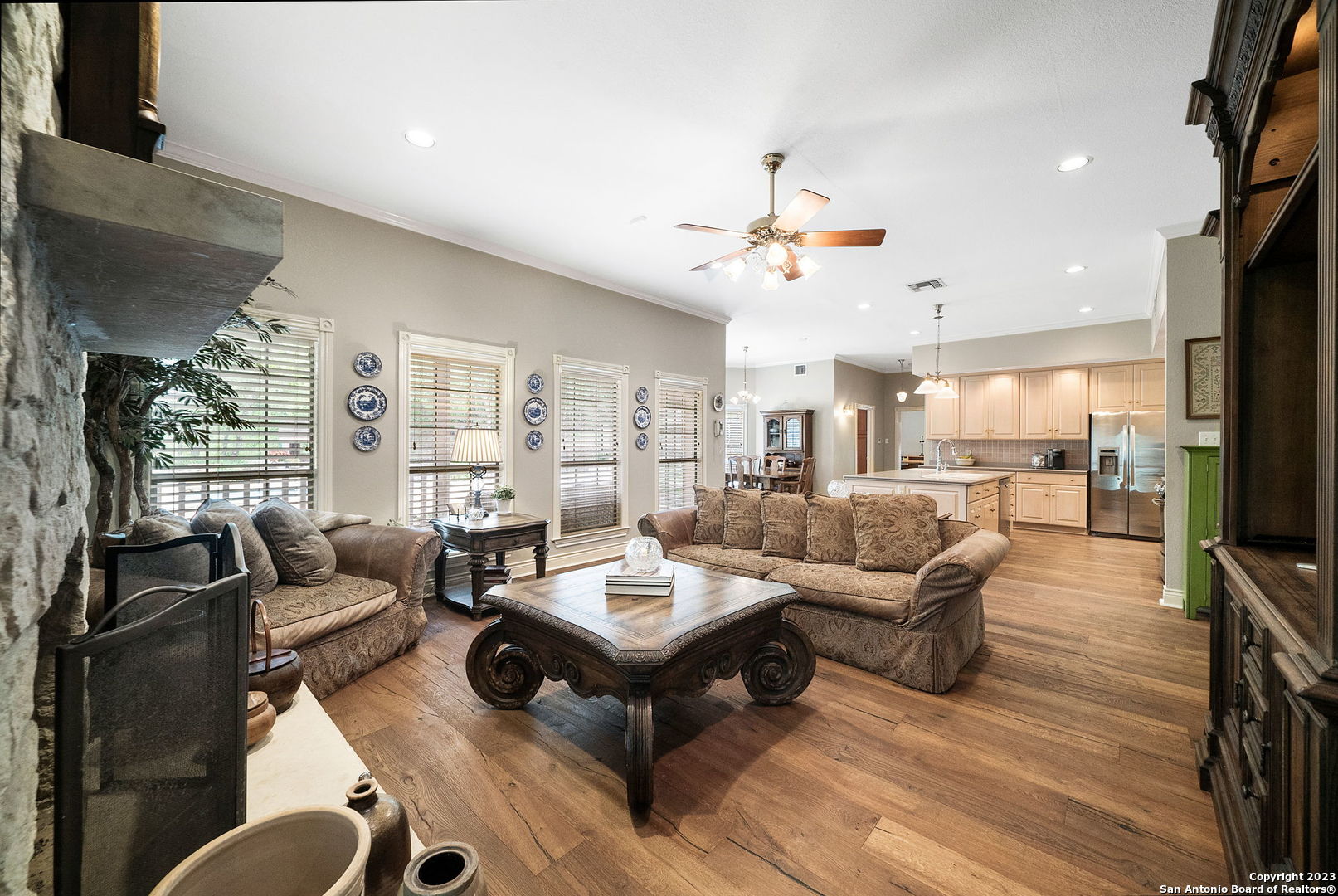 a living room with furniture kitchen view and a wooden floor