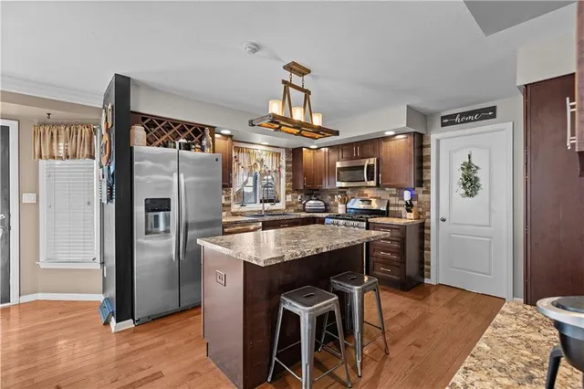 a kitchen with stainless steel appliances granite countertop a refrigerator and a stove top oven