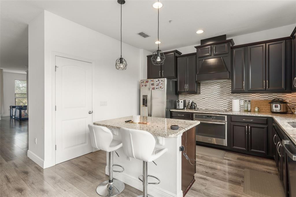 10814 Sunset Ridge Lane Orlando, FL 32832 - Photo 16 of 42 a kitchen with stainless steel appliances granite countertop a sink a stove a refrigerator and island with wooden floor