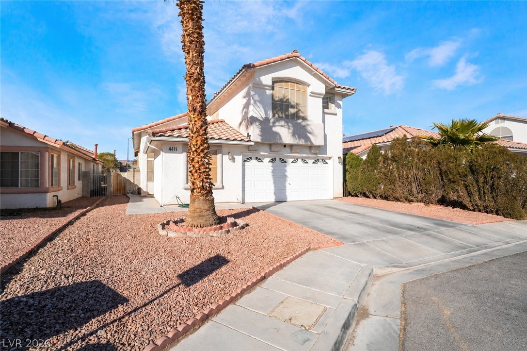 4411 Elk Point Circle Las Vegas, NV 89147 - Photo 3 of 40 This residence features a broad concrete driveway leading to a double garage, set against a clear blue sky.