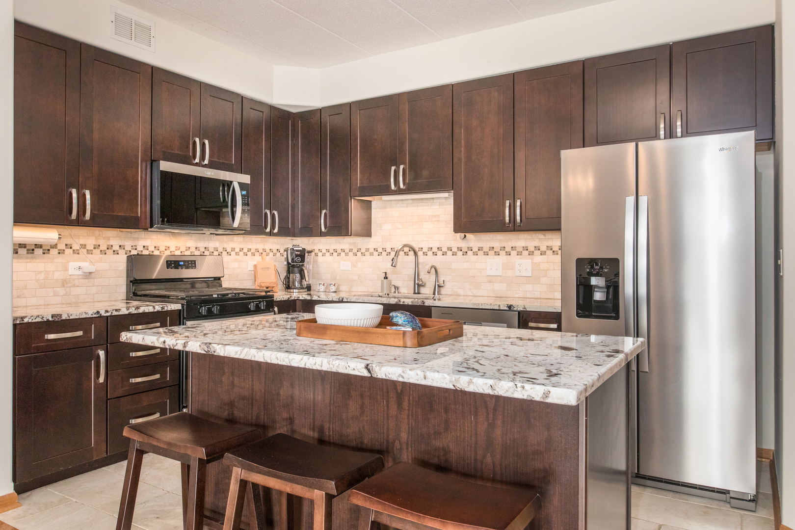 1705 Pavilion Way, Unit 401 Park Ridge, IL 60068 - Photo 10 of 25 a kitchen with kitchen island granite countertop a stove refrigerator and microwave