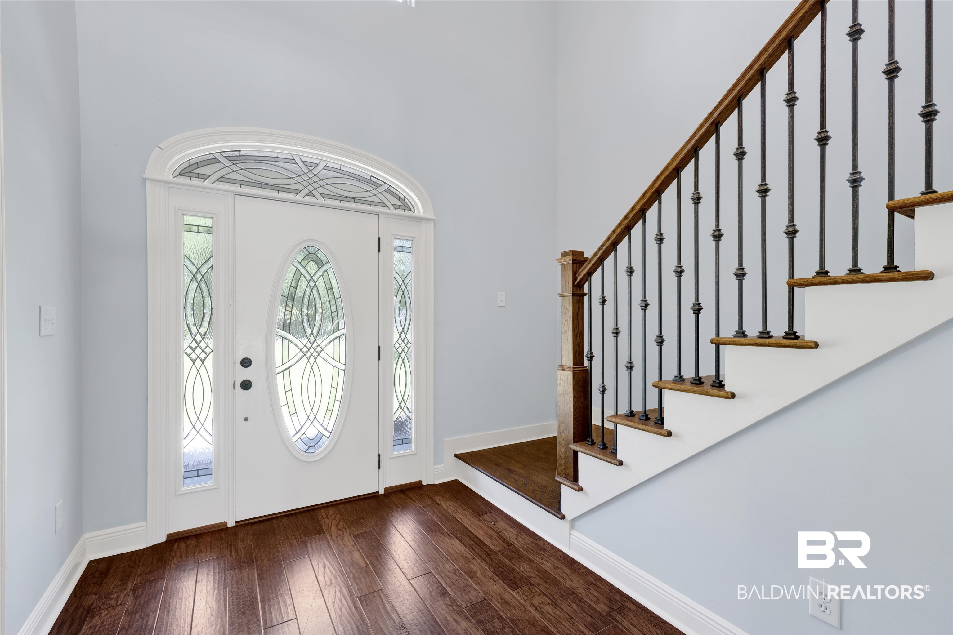 12944 Anna's Way Stapleton, AL 36578 - Photo 33 of 64 Entryway featuring a decorative transom and sidelight windows, a solid wood-finish staircase with wrought iron balusters, and dark wood-finish flooring