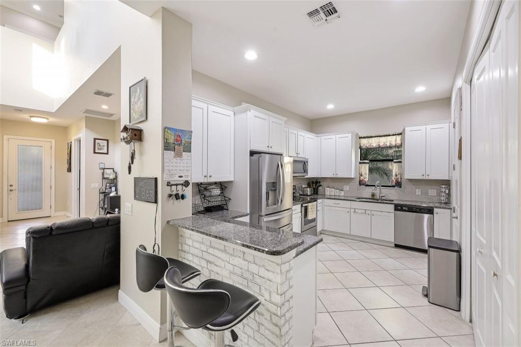 1316 Kendari Terrace Naples, FL 34113 - Photo 6 of 31 a kitchen with stainless steel appliances granite countertop a refrigerator and a sink