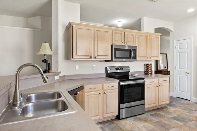 a kitchen with white cabinets a sink stove and microwave