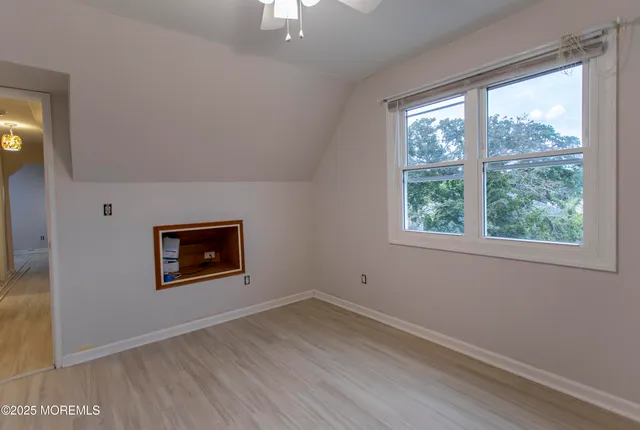 a view of an empty room with wooden floor and windows