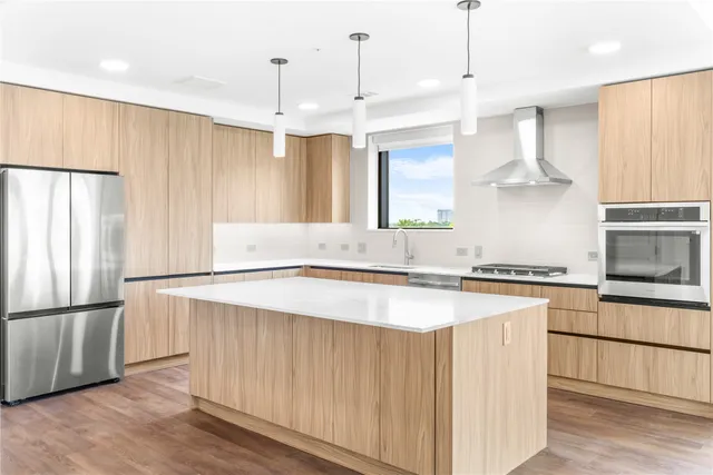 a kitchen with stainless steel appliances granite countertop a refrigerator a sink dishwasher a stove and a refrigerator