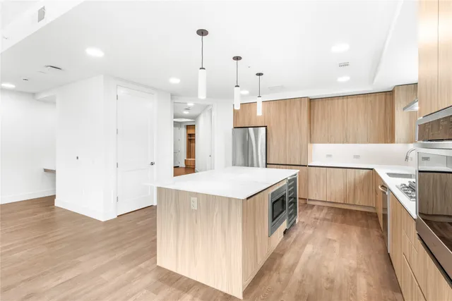 a kitchen with a sink a counter top space stainless steel appliances and a ceiling fan
