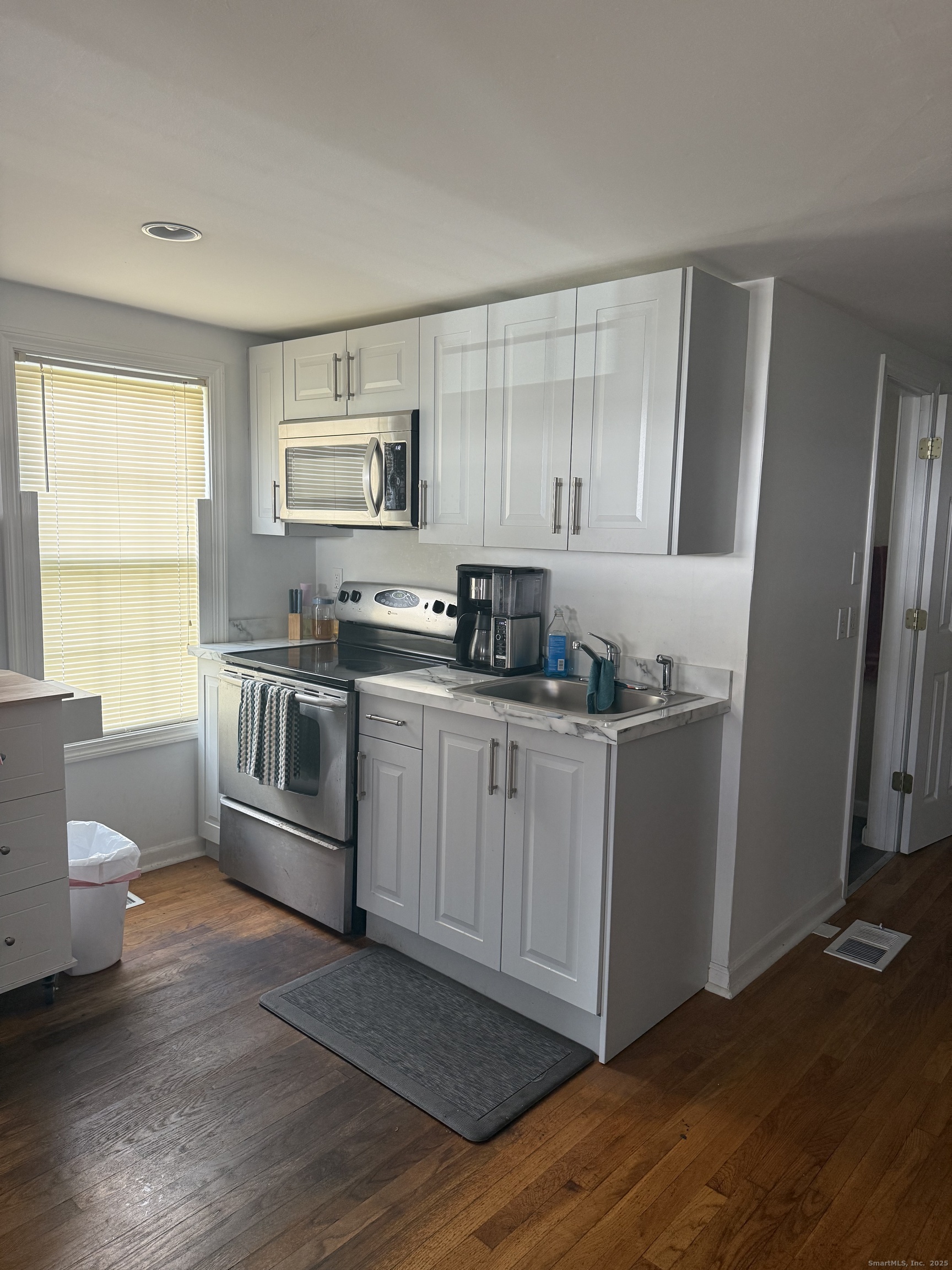 1347 East Main Street Meriden, CT 06450 - Photo 2 of 4 a kitchen with granite countertop a sink cabinets and wooden floor