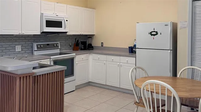 a kitchen with stainless steel appliances granite countertop a refrigerator a sink a stove and white cabinets