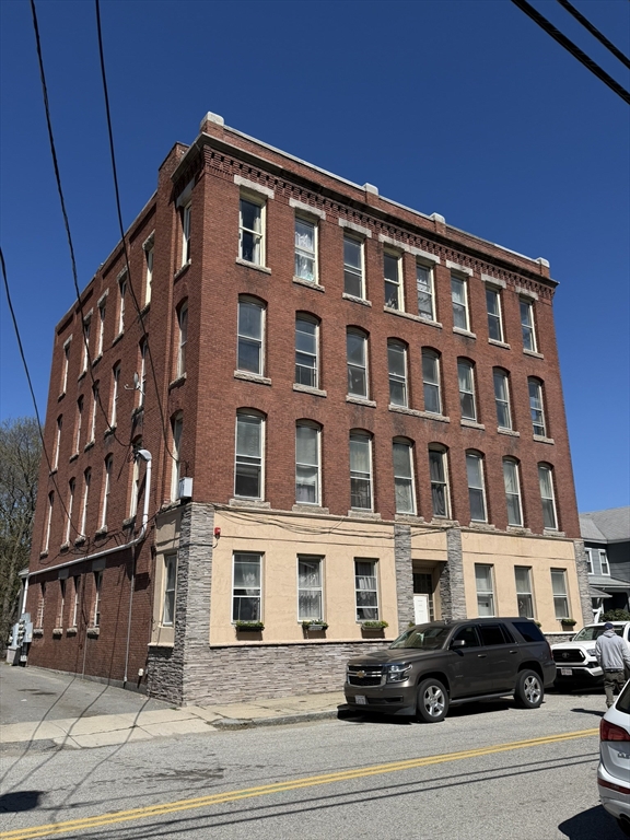 112 School Street Clinton, MA 01510 - Photo 1 of 20 a front view of a building with lot of cars and trees