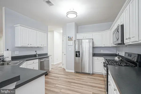 a kitchen with granite countertop a refrigerator stove and sink with wooden floor