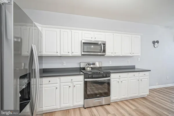 a kitchen with stainless steel appliances granite countertop white cabinets sink and a microwave